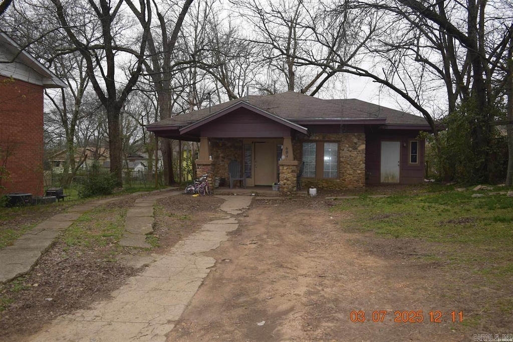 view of front of house with stone siding and a shingled roof