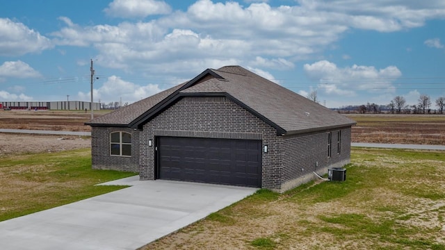 view of home's exterior featuring brick siding, a shingled roof, concrete driveway, central AC, and a lawn