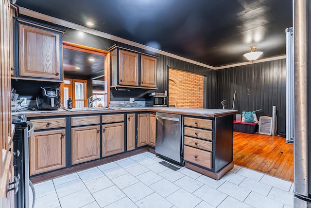 kitchen with a peninsula, light tile patterned flooring, a sink, stainless steel appliances, and crown molding