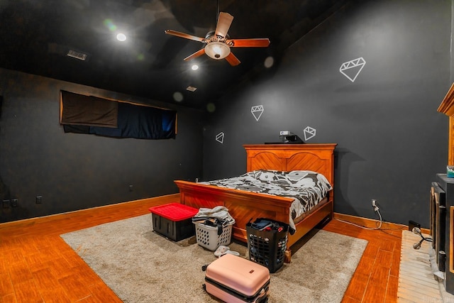 bedroom featuring visible vents, ceiling fan, baseboards, vaulted ceiling, and wood finished floors