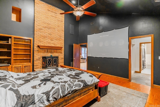 bedroom featuring a fireplace, wood finished floors, baseboards, and high vaulted ceiling