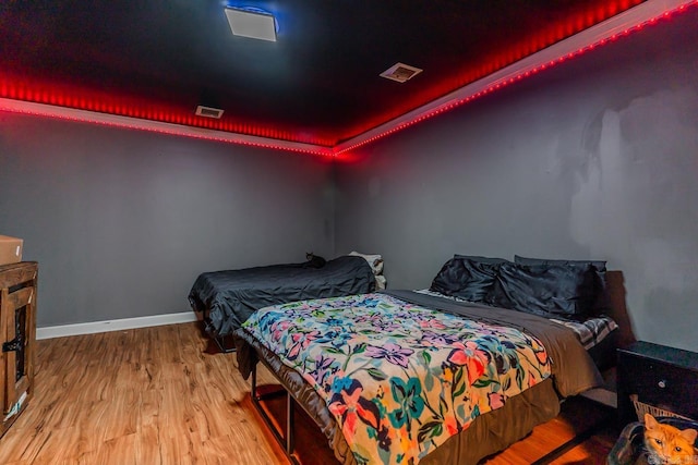 bedroom with visible vents, baseboards, and wood finished floors