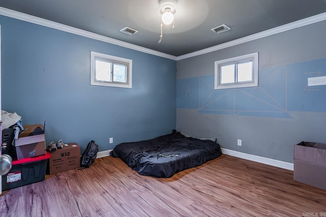 bedroom with visible vents, wood finished floors, multiple windows, and ornamental molding