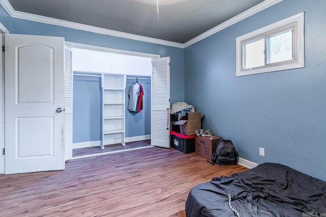 bedroom featuring a closet, wood finished floors, baseboards, and ornamental molding