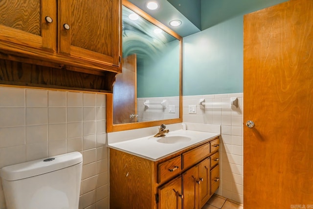 bathroom featuring toilet, tile walls, wainscoting, and vanity