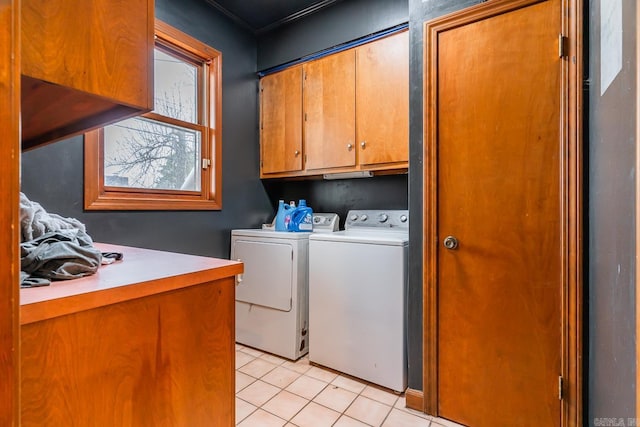 clothes washing area with washing machine and dryer, light tile patterned flooring, and cabinet space