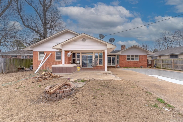 back of property with brick siding, an outdoor fire pit, central AC unit, and fence private yard