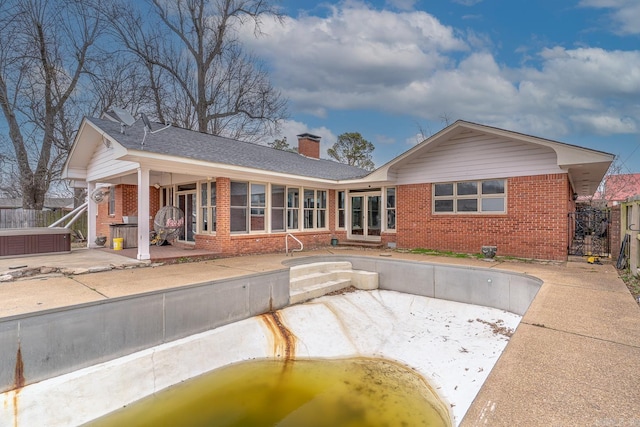 rear view of property featuring brick siding, a chimney, a gate, and fence