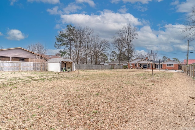 view of yard with an outbuilding, a storage shed, and a fenced backyard