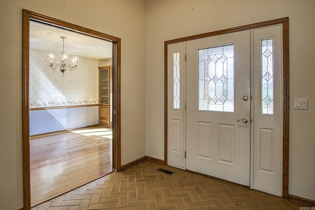 entryway with a notable chandelier, baseboards, and brick floor