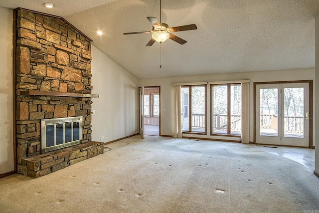 unfurnished living room with lofted ceiling, a textured ceiling, a stone fireplace, and carpet flooring