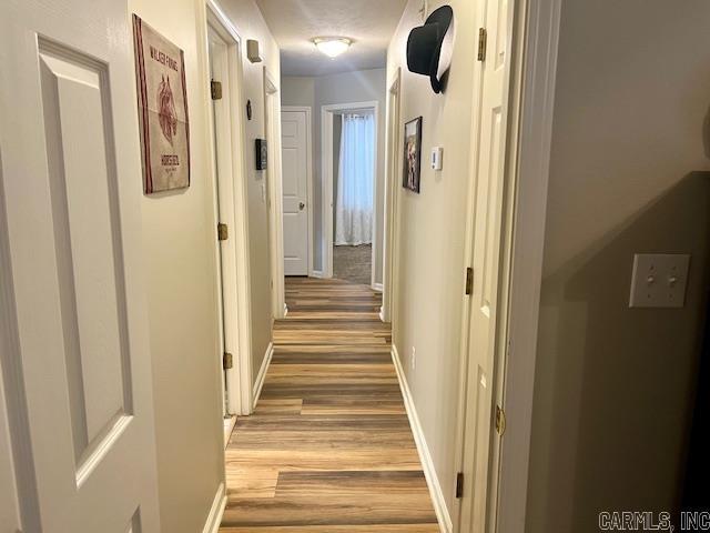 hall featuring light wood-style floors and baseboards