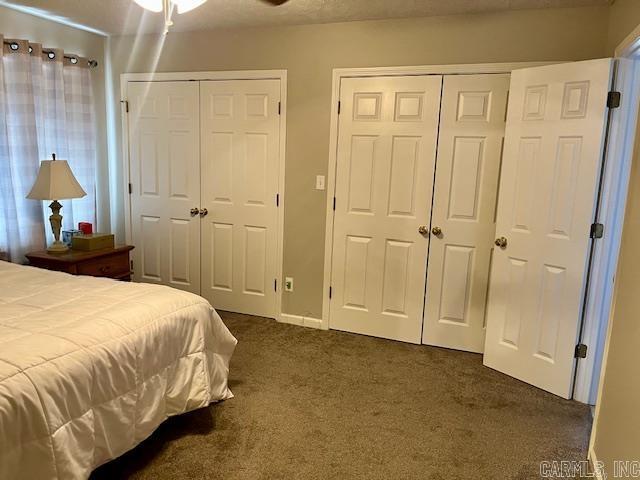 bedroom with multiple closets and dark colored carpet