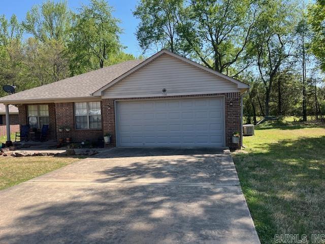ranch-style home featuring brick siding, driveway, an attached garage, and a front lawn