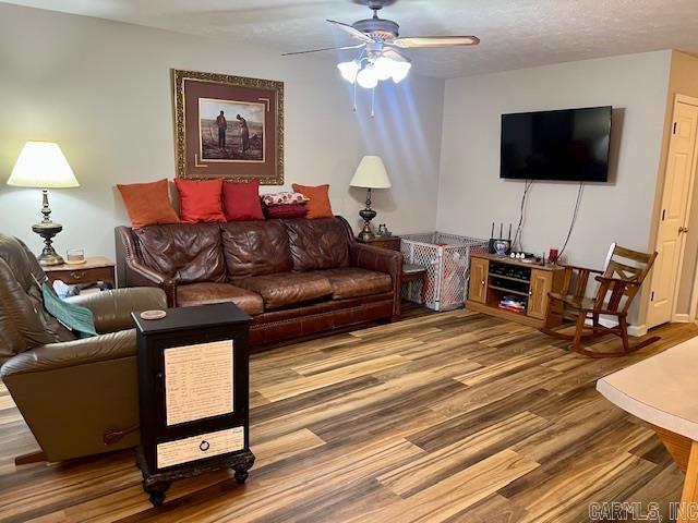 living area featuring a ceiling fan, wood finished floors, and a textured ceiling