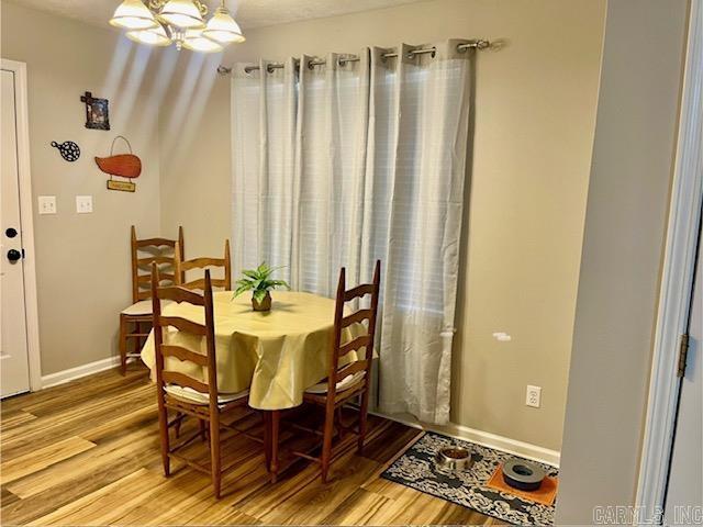 dining area with baseboards, a chandelier, and light wood finished floors