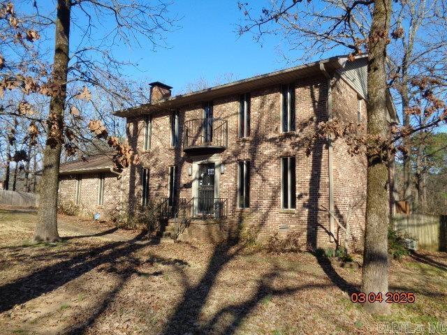 view of property exterior featuring brick siding, a balcony, and a chimney