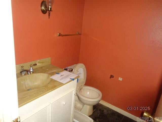 half bathroom with vanity, toilet, baseboards, and tile patterned flooring