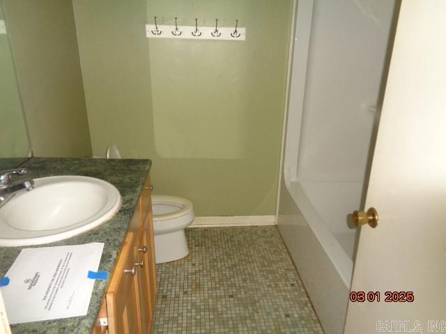 bathroom featuring vanity, toilet, a tub, and baseboards