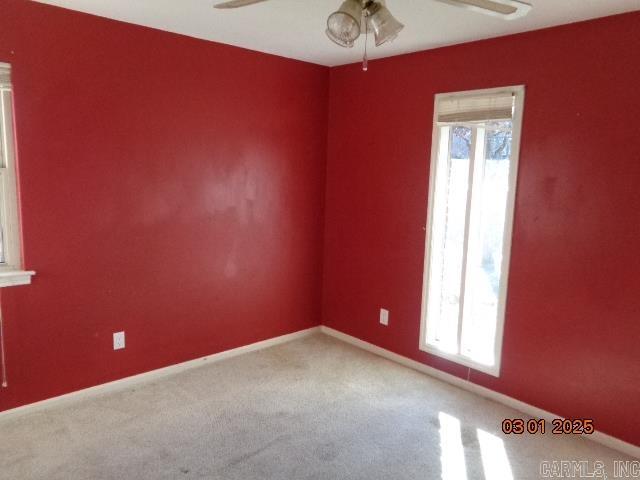 carpeted empty room featuring plenty of natural light, baseboards, and a ceiling fan