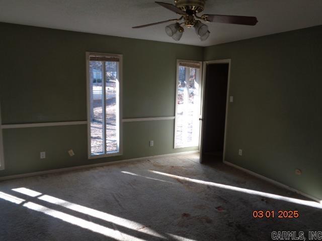 carpeted empty room featuring ceiling fan and baseboards