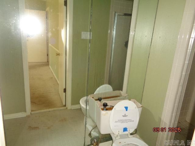 bathroom featuring a stall shower and toilet