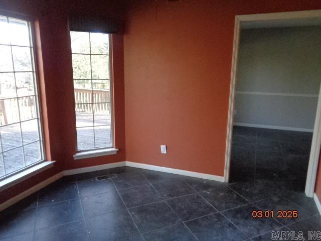 unfurnished room with visible vents, baseboards, and dark tile patterned flooring