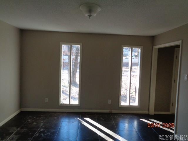 unfurnished room featuring plenty of natural light and baseboards