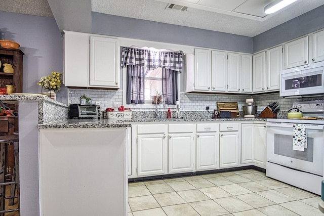 kitchen with visible vents, white appliances, white cabinetry, and a sink