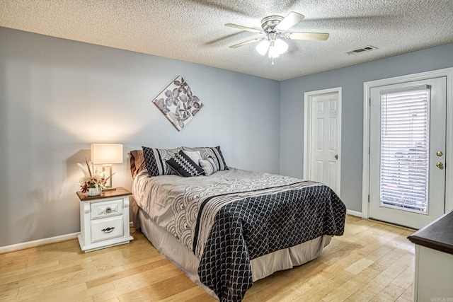 bedroom featuring light wood-type flooring, visible vents, baseboards, and a textured ceiling