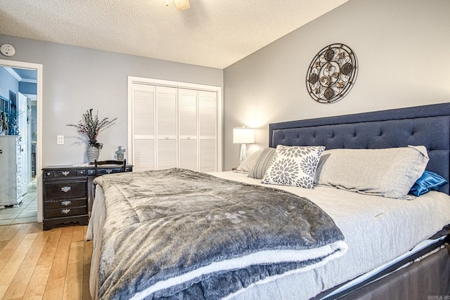 bedroom featuring a ceiling fan, wood finished floors, a closet, and a textured ceiling