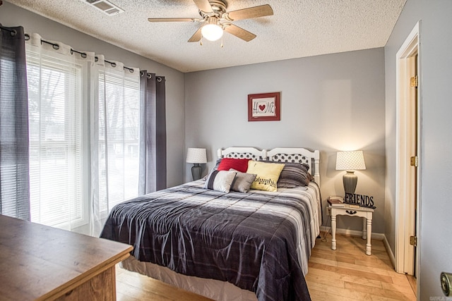 bedroom featuring visible vents, light wood-style flooring, a textured ceiling, and multiple windows