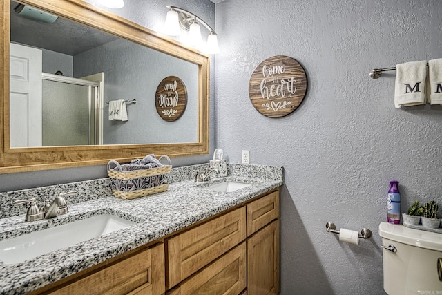 bathroom with toilet, a textured wall, a stall shower, and a sink