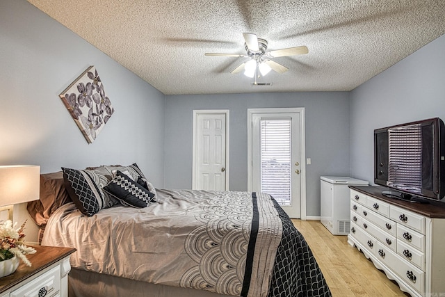 bedroom with a ceiling fan, visible vents, light wood-style flooring, a textured ceiling, and access to outside