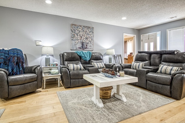 living room featuring light wood-style flooring, recessed lighting, visible vents, and a textured ceiling