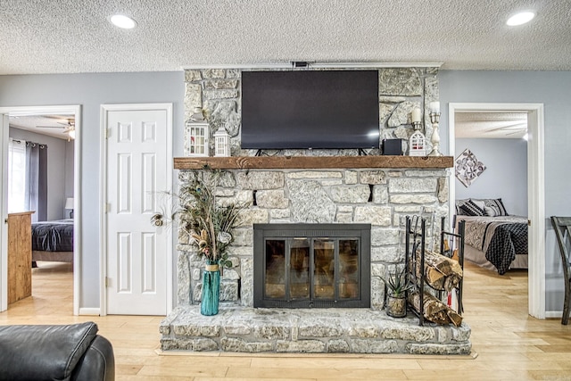 details featuring a stone fireplace, a textured ceiling, baseboards, and wood finished floors