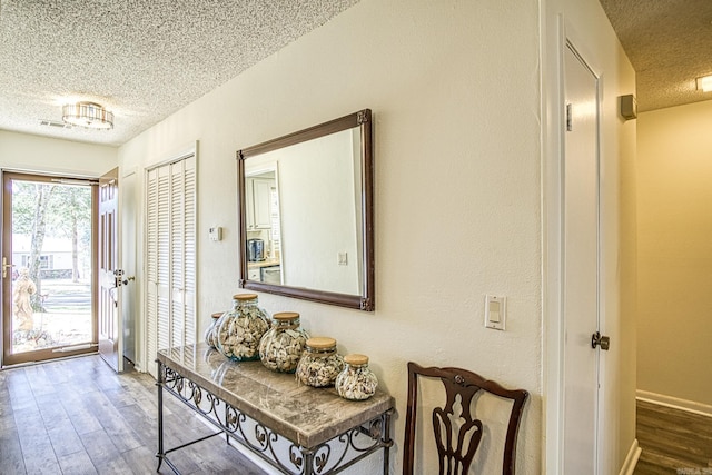 doorway to outside with wood finished floors, baseboards, and a textured ceiling