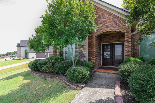 doorway to property with brick siding, stone siding, french doors, and a yard