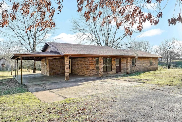 view of front of property with an attached carport, brick siding, driveway, and a front lawn