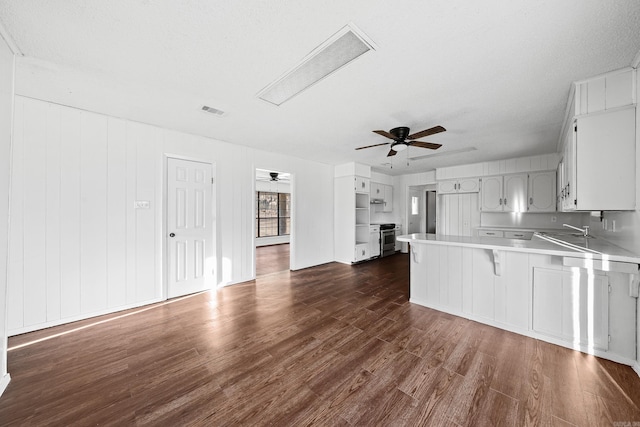 kitchen featuring visible vents, dark wood-style floors, a peninsula, light countertops, and ceiling fan