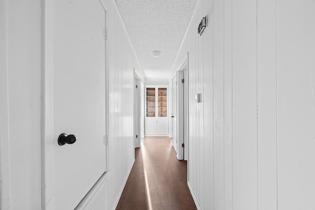 corridor with dark wood-type flooring and a textured ceiling