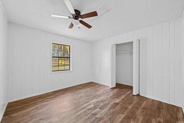 unfurnished bedroom with a closet, a textured ceiling, dark wood-type flooring, and a ceiling fan