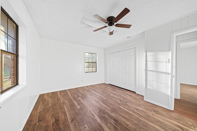 unfurnished bedroom featuring visible vents, ceiling fan, wood finished floors, a closet, and a textured ceiling