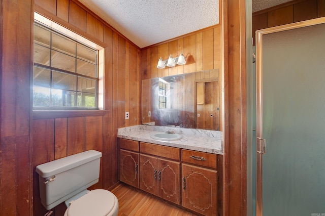 bathroom featuring wooden walls, toilet, and a textured ceiling