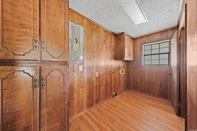 interior space with electric panel, a textured ceiling, wood finished floors, and wood walls