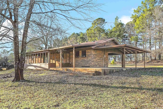 view of home's exterior with a carport, brick siding, and a sunroom