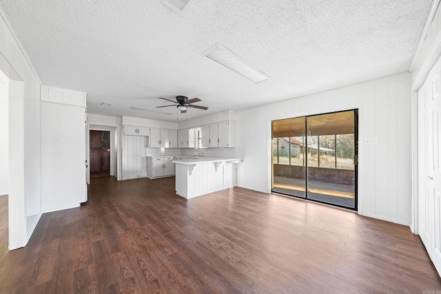 unfurnished living room featuring dark wood finished floors, visible vents, a textured ceiling, and a ceiling fan