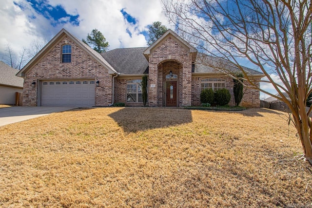 traditional home featuring concrete driveway, brick siding, a front yard, and a shingled roof