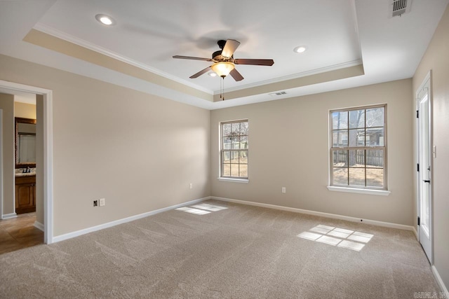 empty room featuring visible vents, a raised ceiling, and carpet