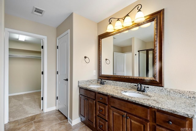 full bath featuring double vanity, a shower with shower door, visible vents, and a sink